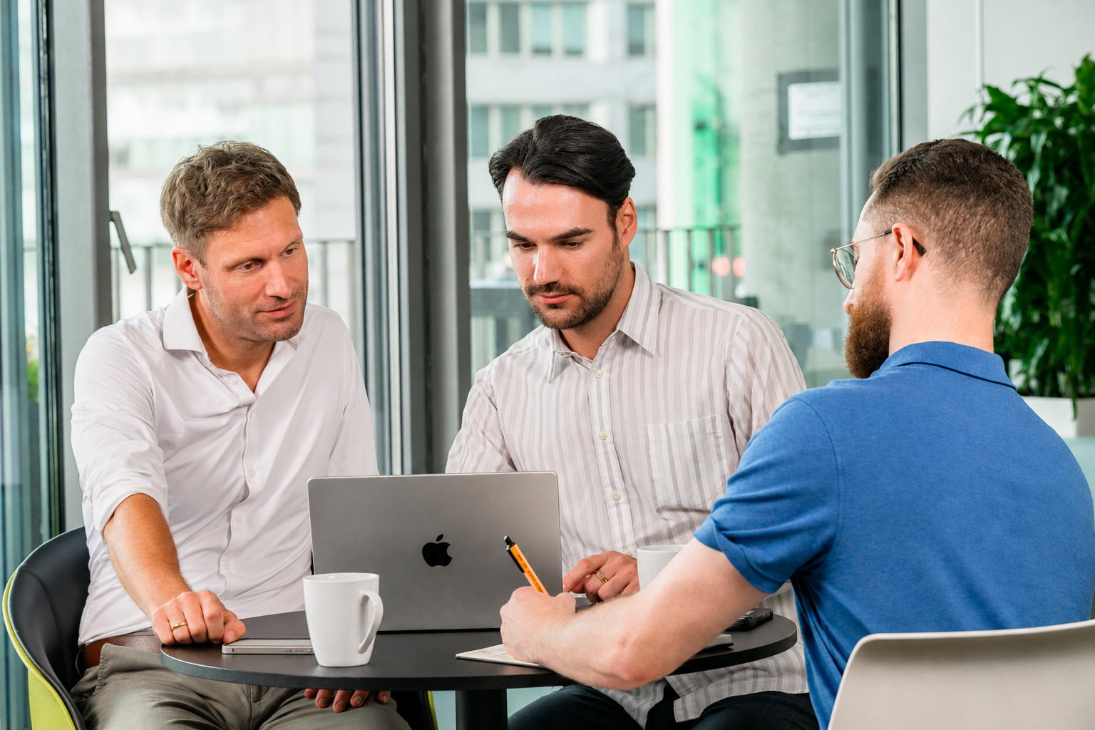 Three Rebuilders Founders sit around a table and look into a laptop.